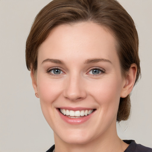 Joyful white young-adult female with medium  brown hair and grey eyes