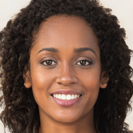 Joyful black young-adult female with long  brown hair and brown eyes