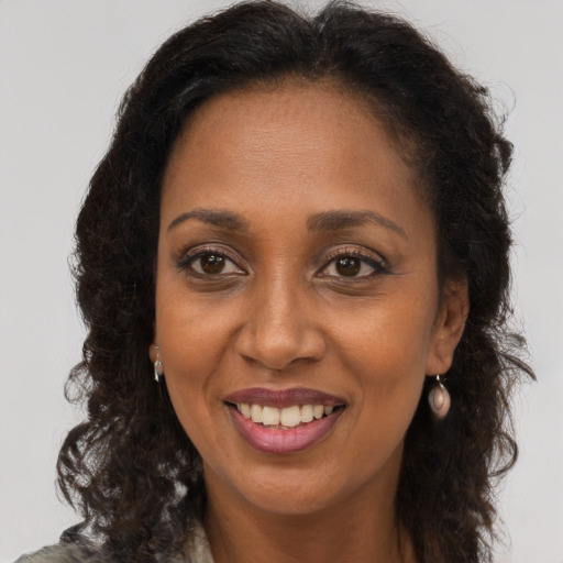 Joyful black adult female with long  brown hair and brown eyes