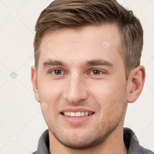 Joyful white young-adult male with short  brown hair and grey eyes