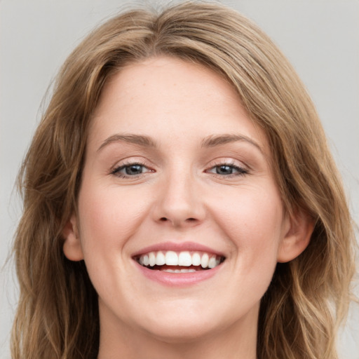 Joyful white young-adult female with long  brown hair and blue eyes