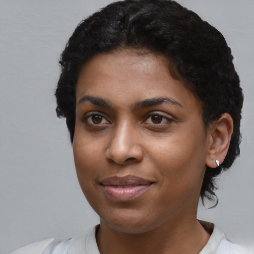 Joyful black young-adult female with short  black hair and brown eyes