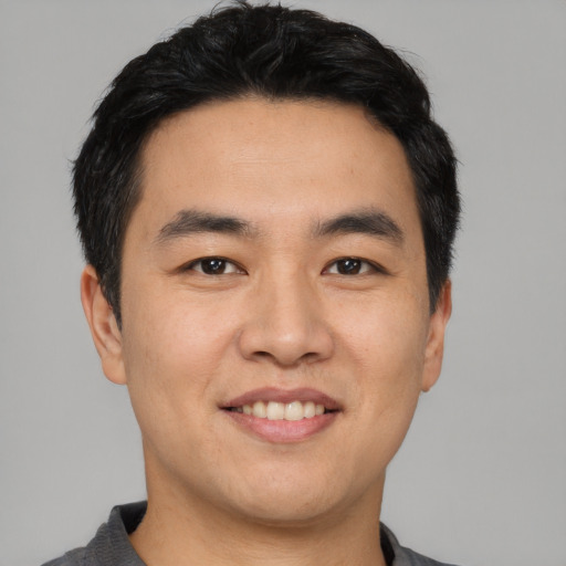 Joyful asian young-adult male with short  black hair and brown eyes