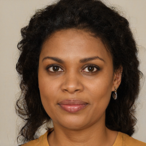 Joyful black young-adult female with long  brown hair and brown eyes