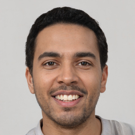 Joyful latino young-adult male with short  black hair and brown eyes