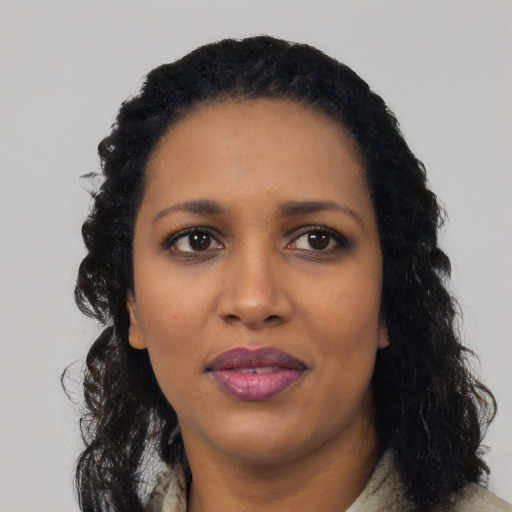 Joyful black young-adult female with long  black hair and brown eyes