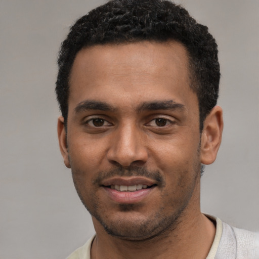 Joyful black young-adult male with short  black hair and brown eyes