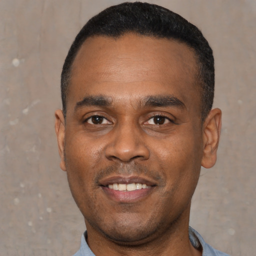 Joyful black young-adult male with short  black hair and brown eyes