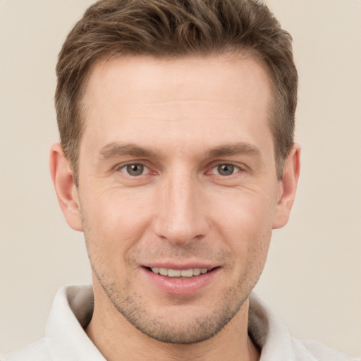 Joyful white young-adult male with short  brown hair and grey eyes