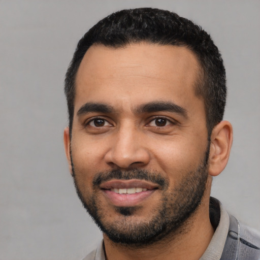 Joyful latino young-adult male with short  black hair and brown eyes