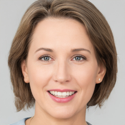 Joyful white young-adult female with medium  brown hair and grey eyes