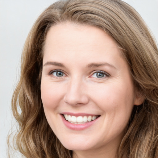 Joyful white young-adult female with long  brown hair and blue eyes