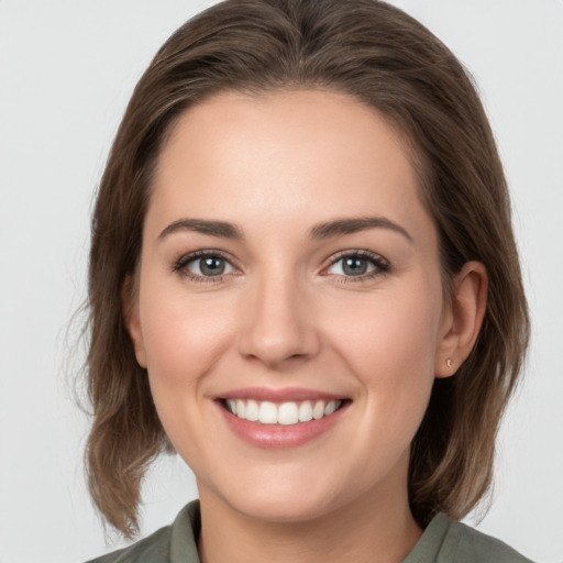 Joyful white young-adult female with medium  brown hair and grey eyes