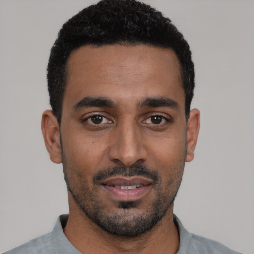 Joyful black young-adult male with short  black hair and brown eyes