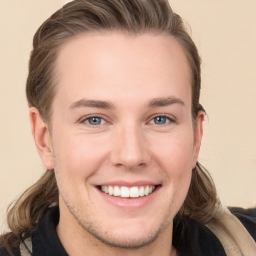 Joyful white young-adult male with long  brown hair and grey eyes