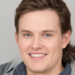 Joyful white young-adult male with medium  brown hair and grey eyes