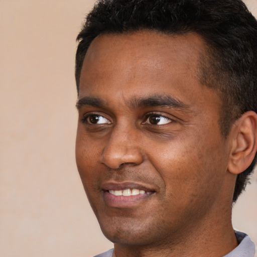 Joyful black young-adult male with short  black hair and brown eyes