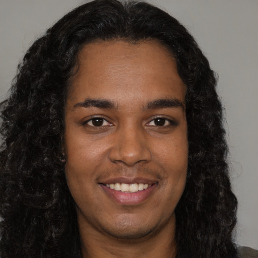 Joyful black young-adult female with long  black hair and brown eyes