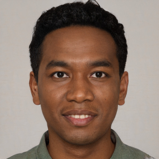 Joyful black young-adult male with short  black hair and brown eyes
