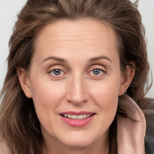 Joyful white adult female with long  brown hair and grey eyes