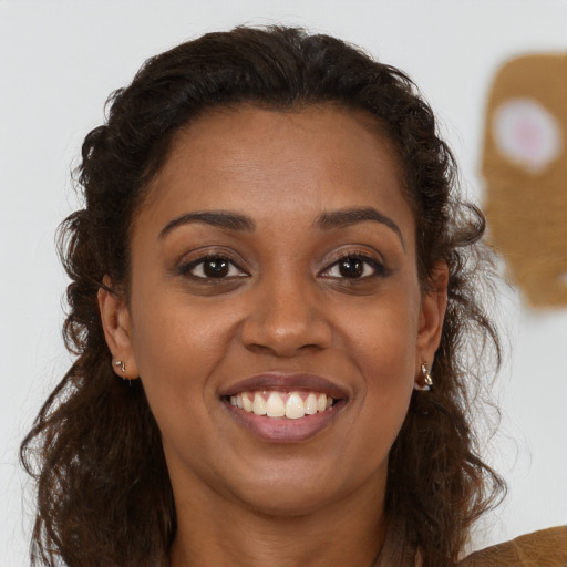 Joyful black young-adult female with long  brown hair and brown eyes