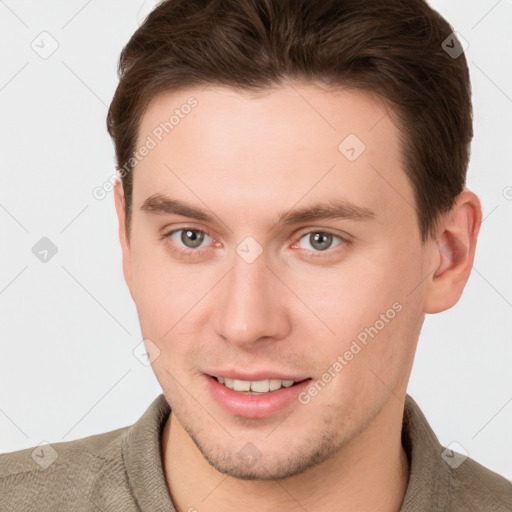 Joyful white young-adult male with short  brown hair and grey eyes