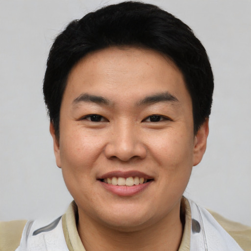 Joyful asian young-adult male with short  black hair and brown eyes