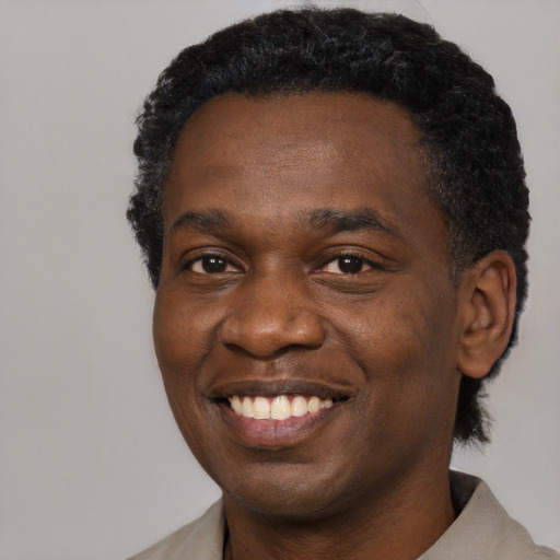 Joyful black young-adult male with short  black hair and brown eyes
