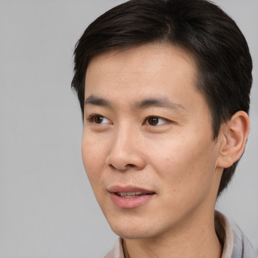 Joyful asian young-adult male with short  brown hair and brown eyes