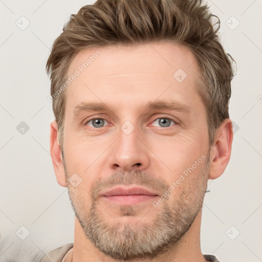 Joyful white young-adult male with short  brown hair and grey eyes