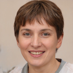 Joyful white young-adult female with medium  brown hair and grey eyes