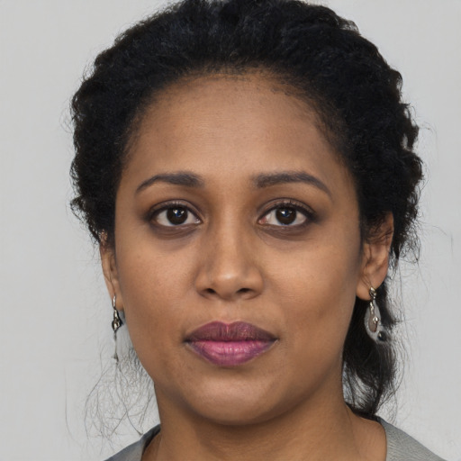 Joyful black young-adult female with long  brown hair and brown eyes