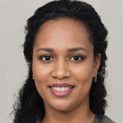 Joyful black young-adult female with long  black hair and brown eyes