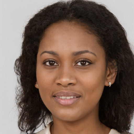 Joyful black young-adult female with long  brown hair and brown eyes