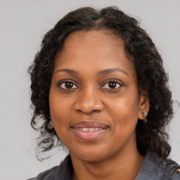 Joyful black young-adult female with long  brown hair and brown eyes