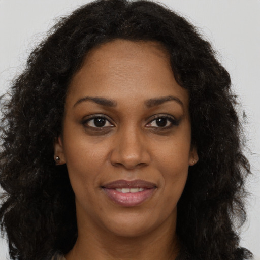 Joyful black young-adult female with long  brown hair and brown eyes