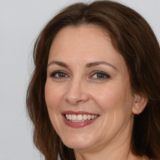 Joyful white adult female with long  brown hair and grey eyes