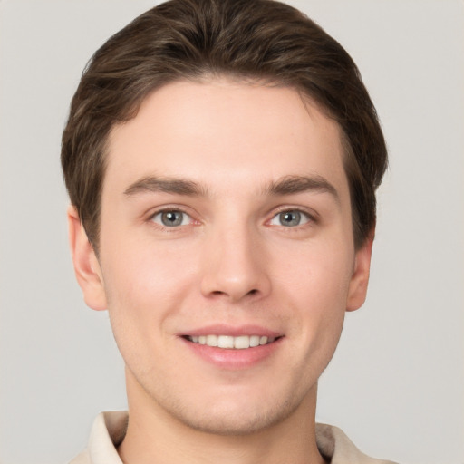 Joyful white young-adult male with short  brown hair and grey eyes