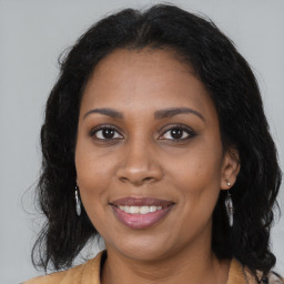 Joyful black young-adult female with long  brown hair and brown eyes