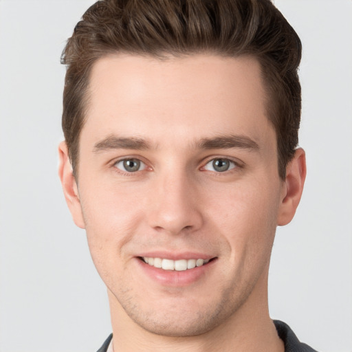 Joyful white young-adult male with short  brown hair and grey eyes