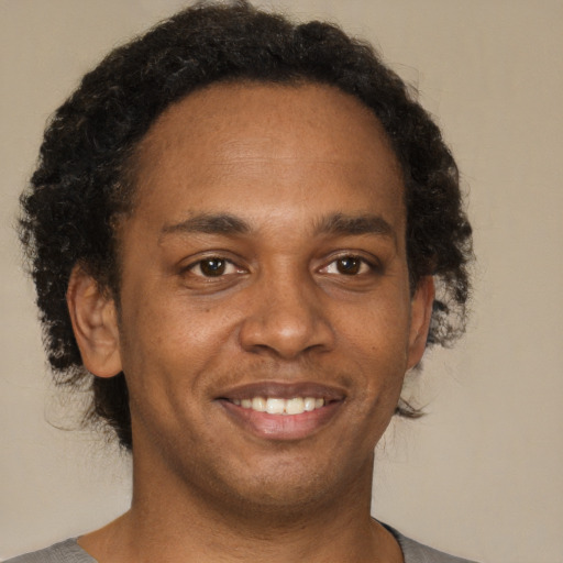 Joyful black young-adult male with short  brown hair and brown eyes