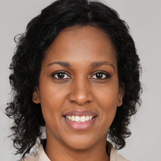 Joyful black young-adult female with long  brown hair and brown eyes