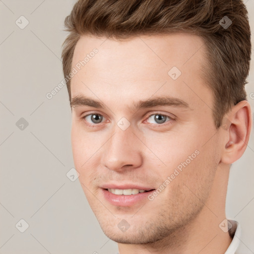 Joyful white young-adult male with short  brown hair and grey eyes