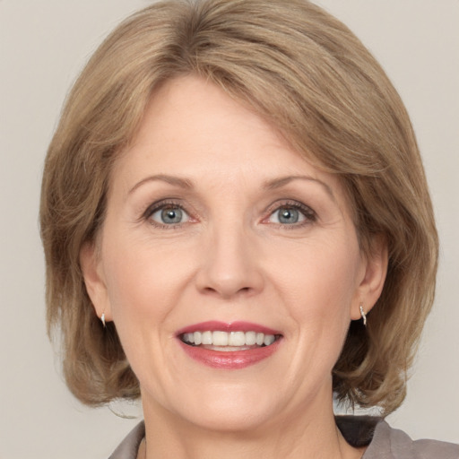 Joyful white adult female with medium  brown hair and grey eyes