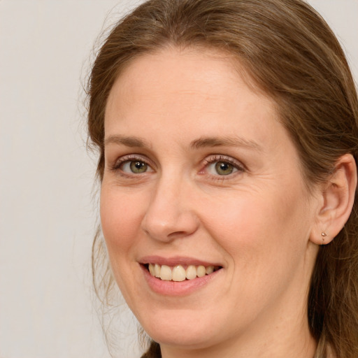 Joyful white adult female with long  brown hair and green eyes