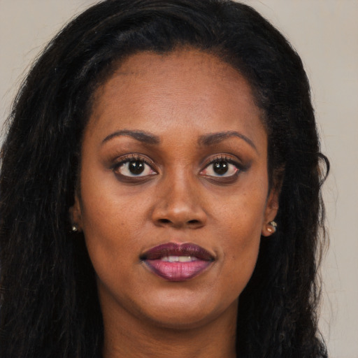 Joyful black adult female with long  brown hair and brown eyes