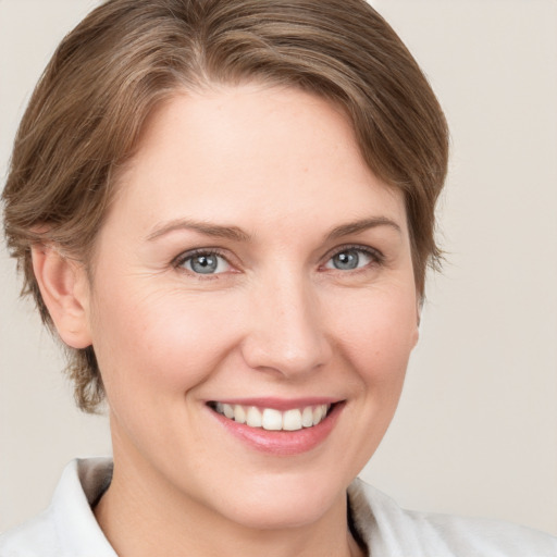 Joyful white young-adult female with medium  brown hair and grey eyes