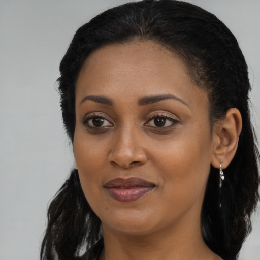 Joyful black young-adult female with long  brown hair and brown eyes