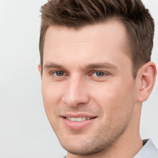 Joyful white young-adult male with short  brown hair and grey eyes