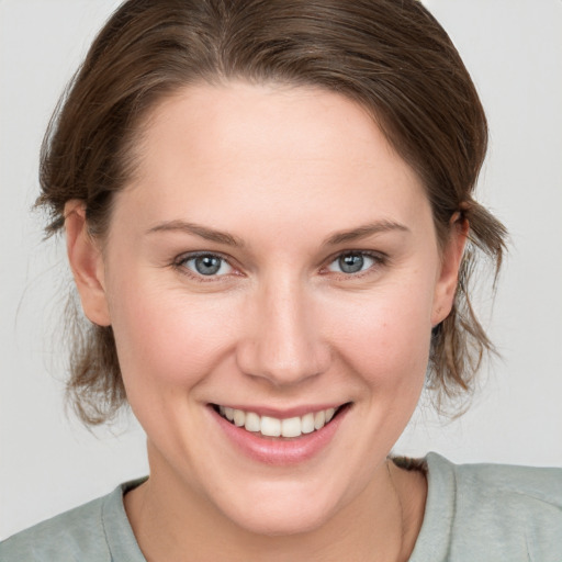 Joyful white young-adult female with medium  brown hair and grey eyes